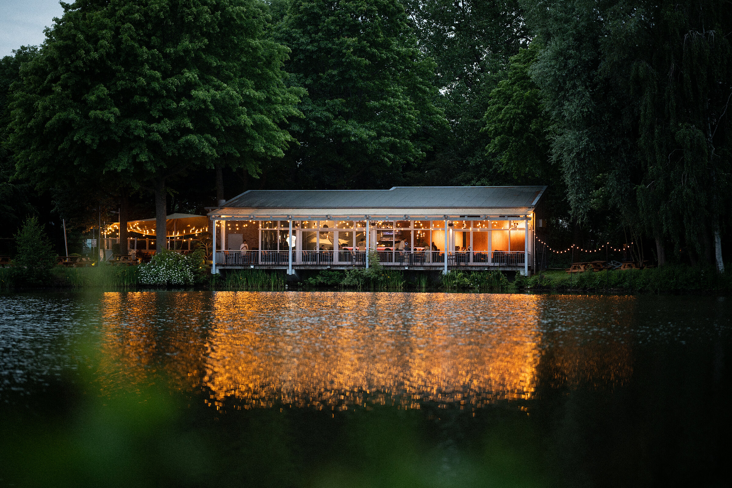 Harry's Haus am See am Abend – Lichter spiegeln sich im See